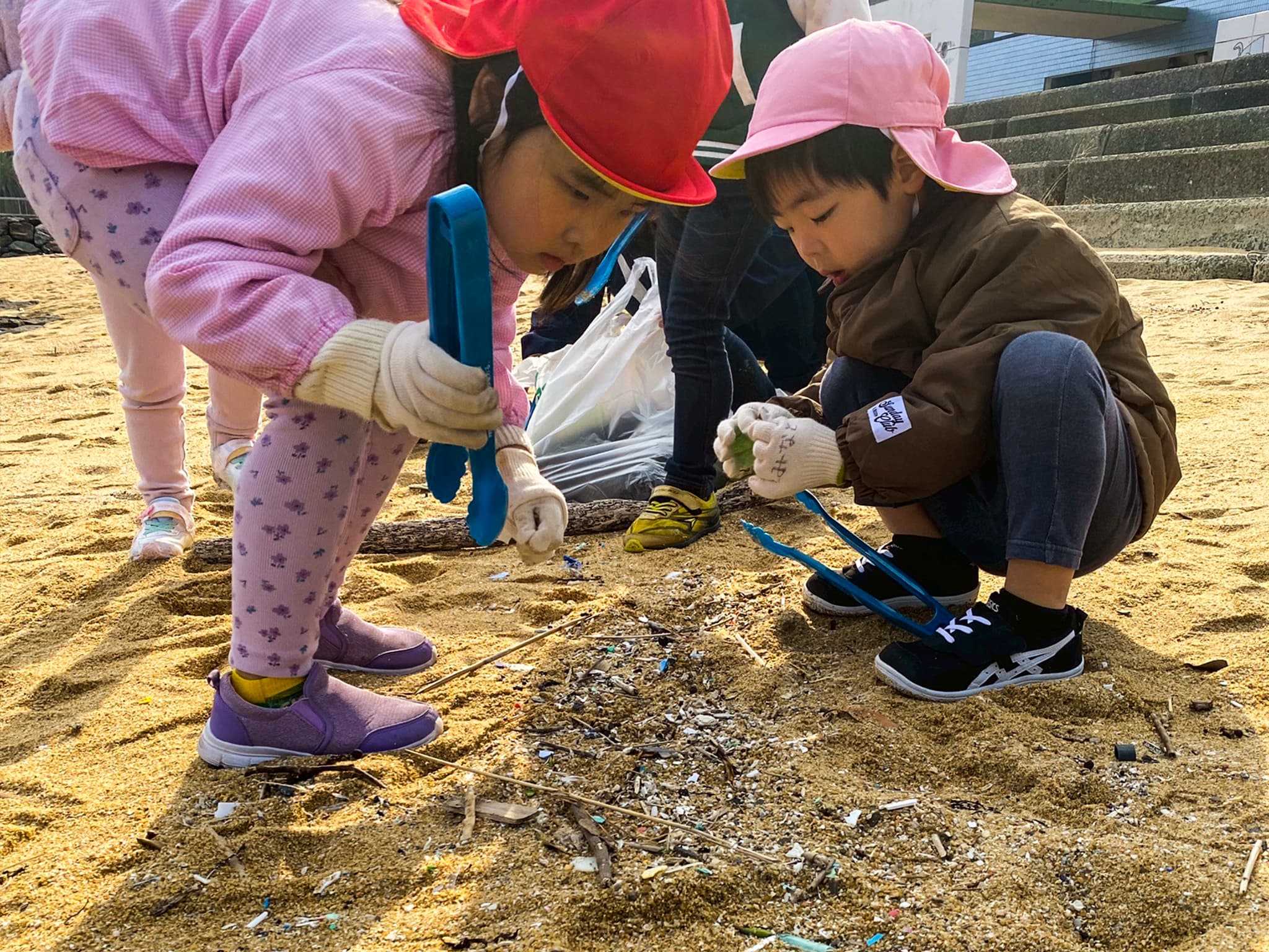 ビーチのマイクロプラスチックを拾う児童