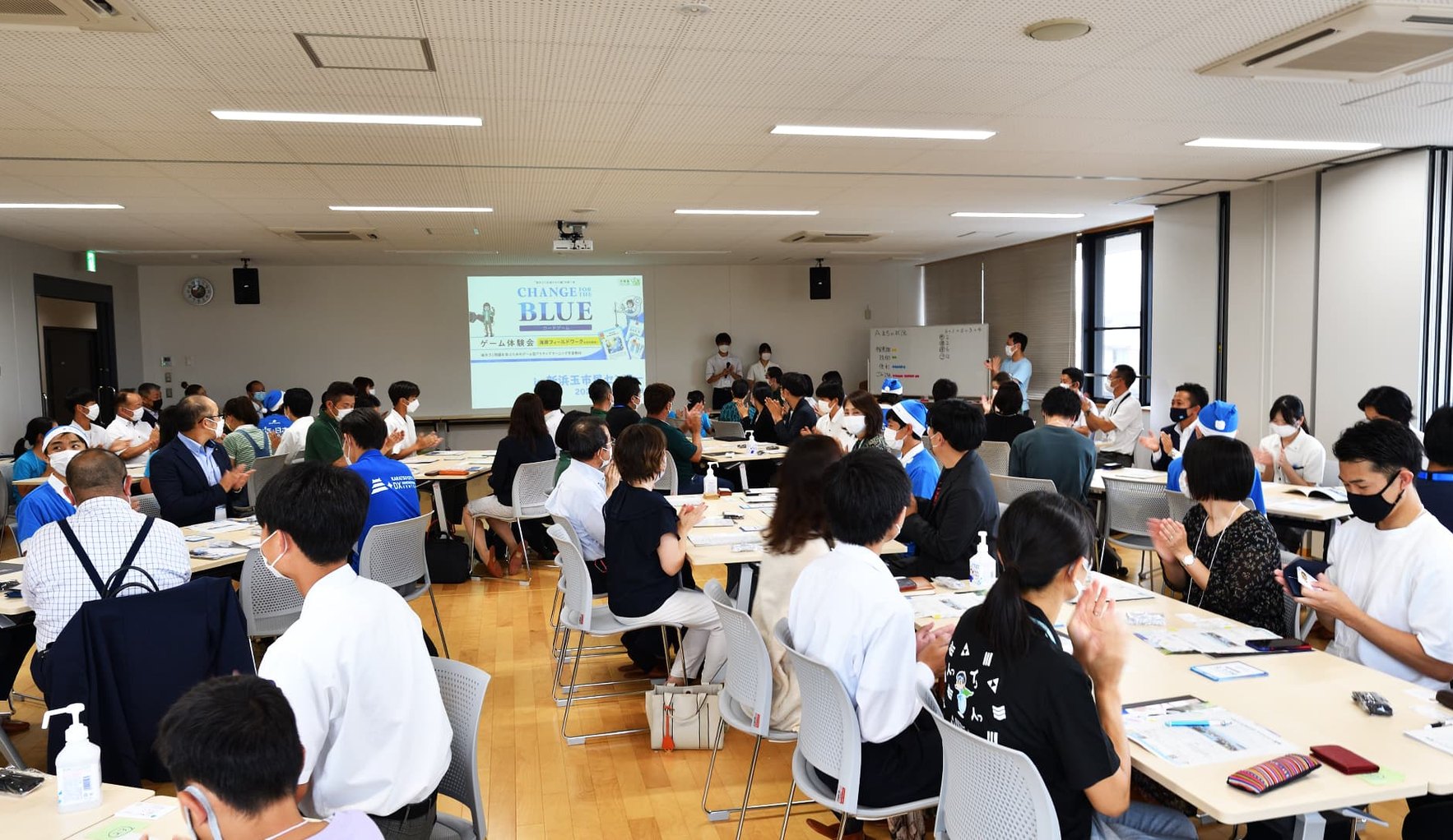 People from companies, government and local groups around tables in a meeting room, playing a business card game about marine litter