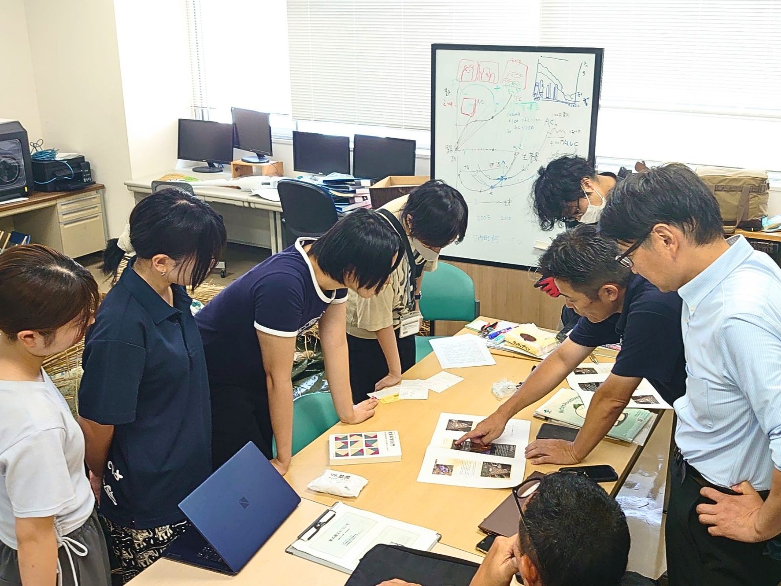 福岡女子大学の研究室で、机に広げた資料や試作品を囲んで話し合う学生と大丸福岡天神店・唐津Farm&Foodのメンバー