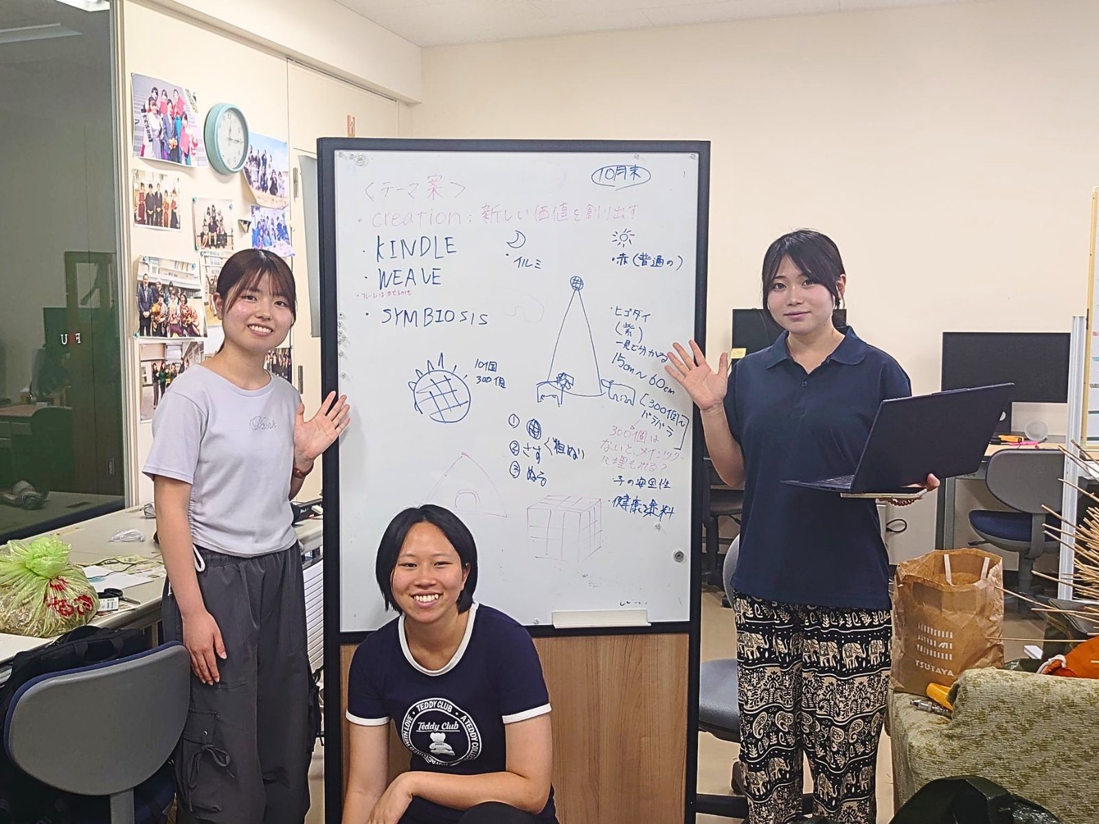 ツリーのスケッチとアイデアを書き込んだホワイトボードの前に立つ、福岡女子大学の学生3名