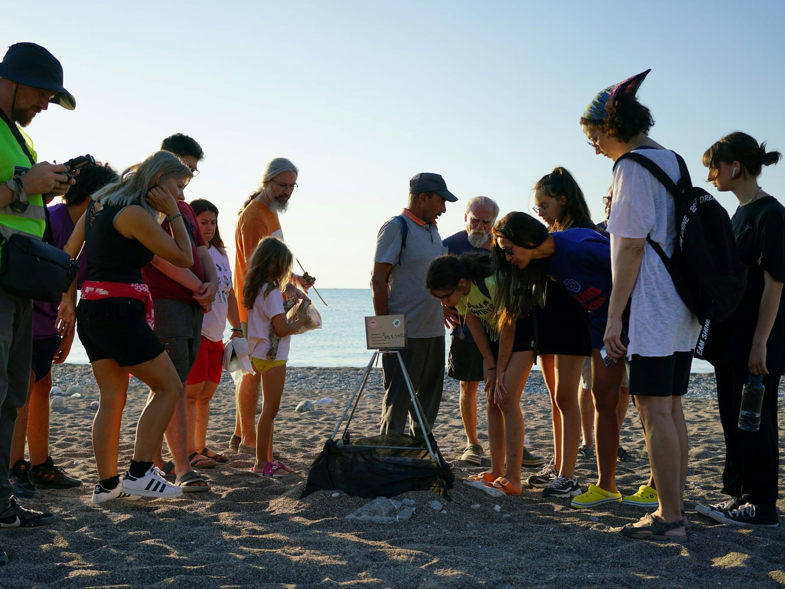 People on a beach listening to a guide and looking at something on the sand