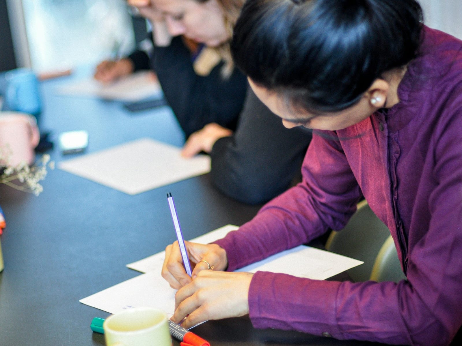 People writing on paper around a table during a training session
