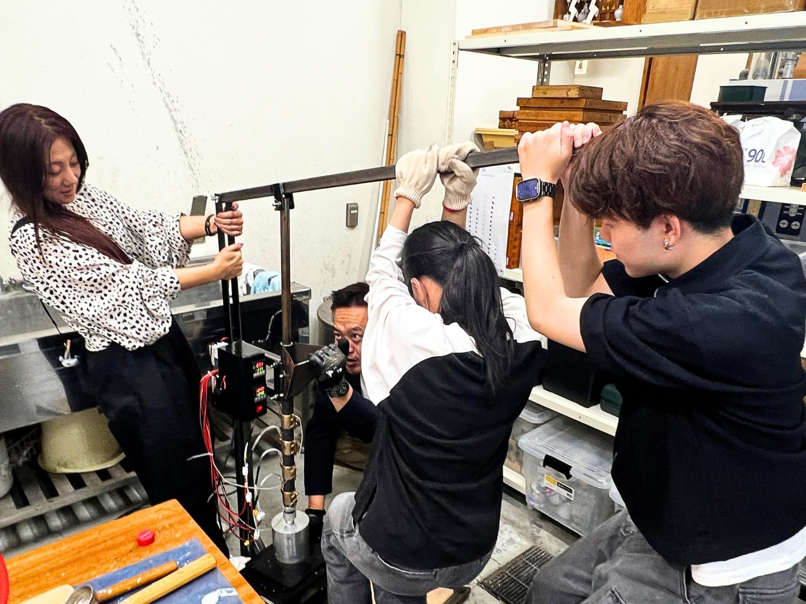 倉敷芸術科学大学の工房で、射出成形機のレバーを押し下げる学生たち