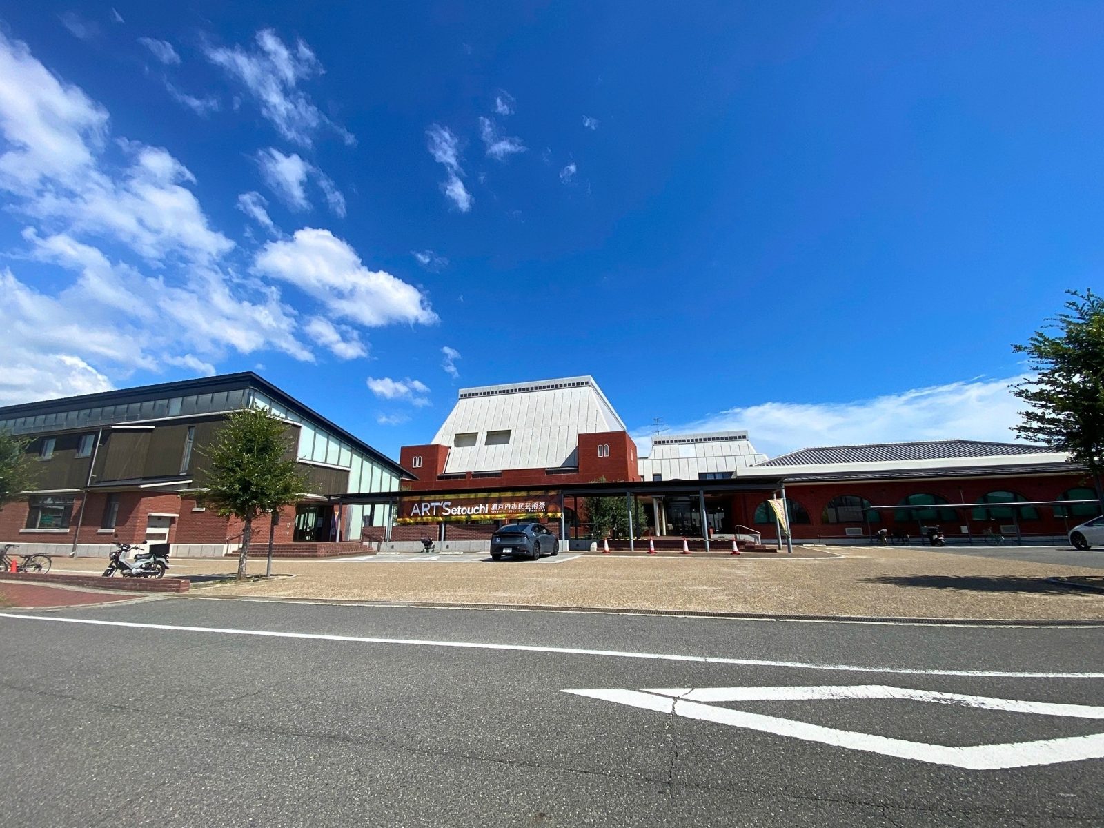 青空の下の瀬戸内市民図書館の外観と、前を走る道路