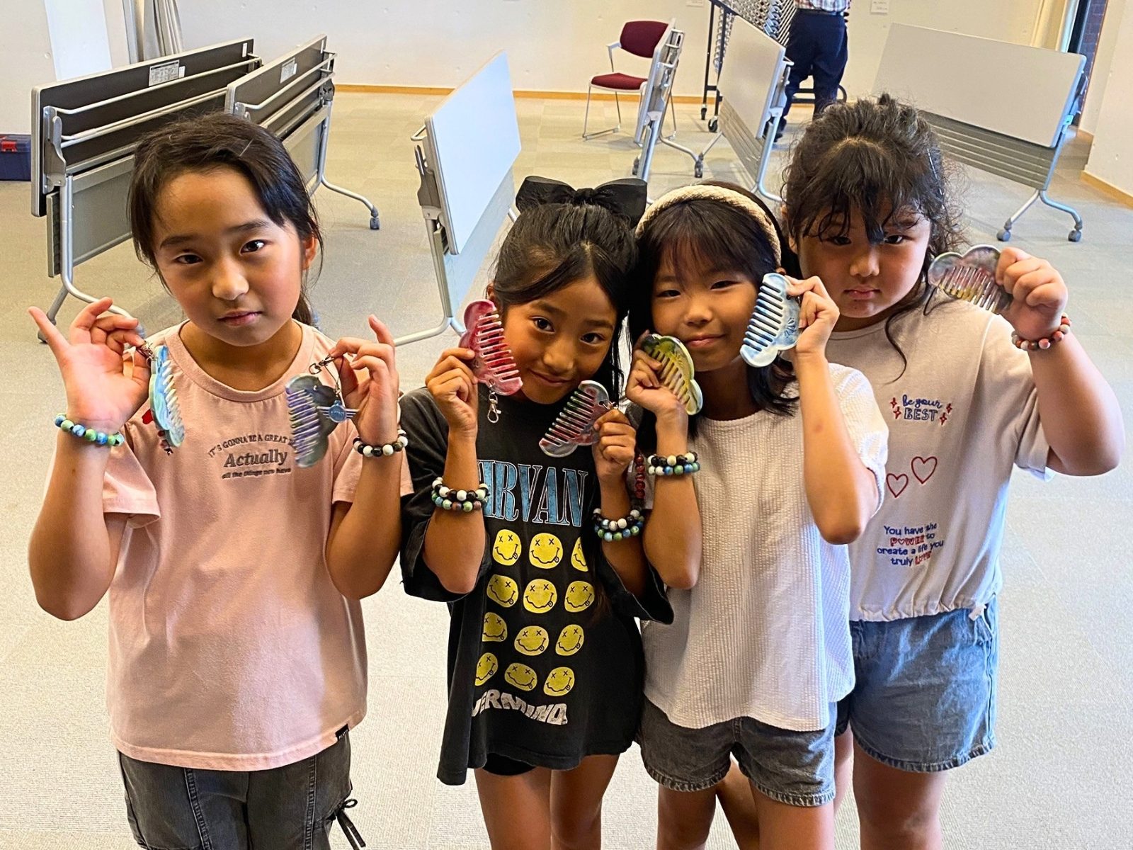 できあがったビーズのブレスレットを手首に着けて、カメラに向かって見せる4人の子どもたち