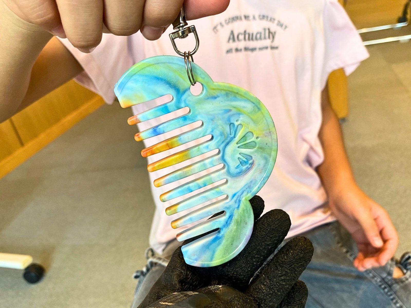 Tシャツの胸元に下げた、青と黄のマーブル模様の松モチーフの櫛「Re comb」のキーホルダー