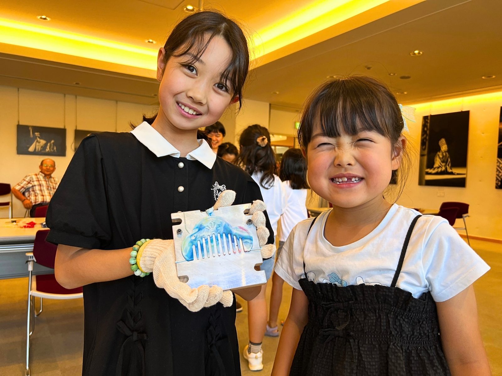 成形したばかりの水色のマーブル模様の櫛を手に笑顔を見せる子どもたち