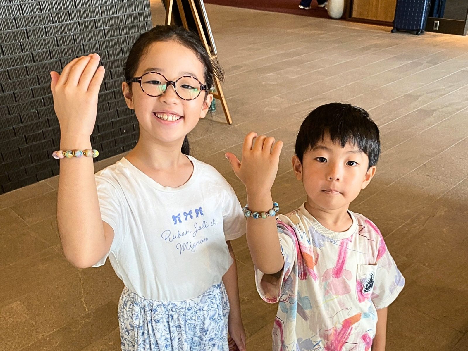 自分でつくったビーズのブレスレットを着けた腕を上げて見せる子どもたち