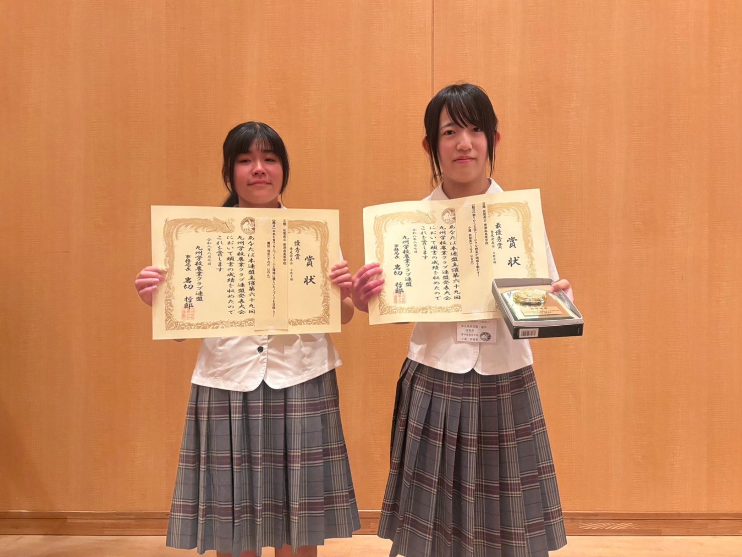意見発表で入賞した唐津南高校の生徒2名。左は分野Ⅱ類2位の賞状、右は分野Ⅲ類最優秀賞の賞状と記念の盾を手にしている