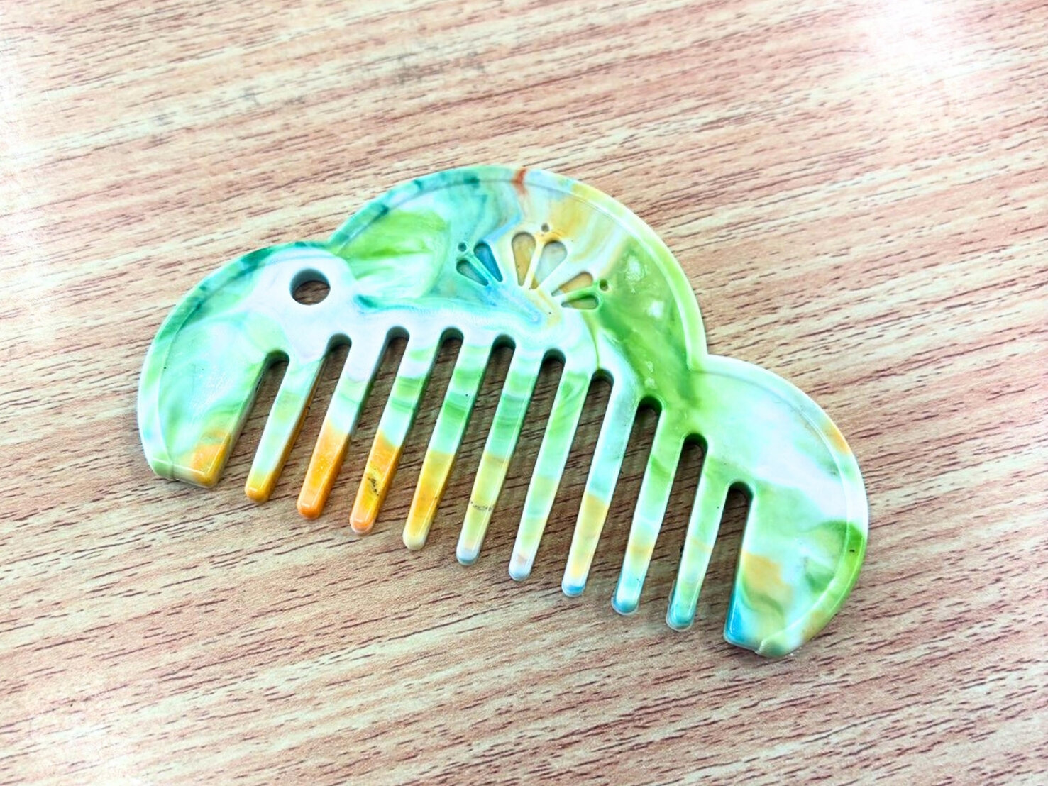 緑や黄色のマーブル模様に仕上がった松モチーフの櫛「Re comb」(仮称)のクローズアップ