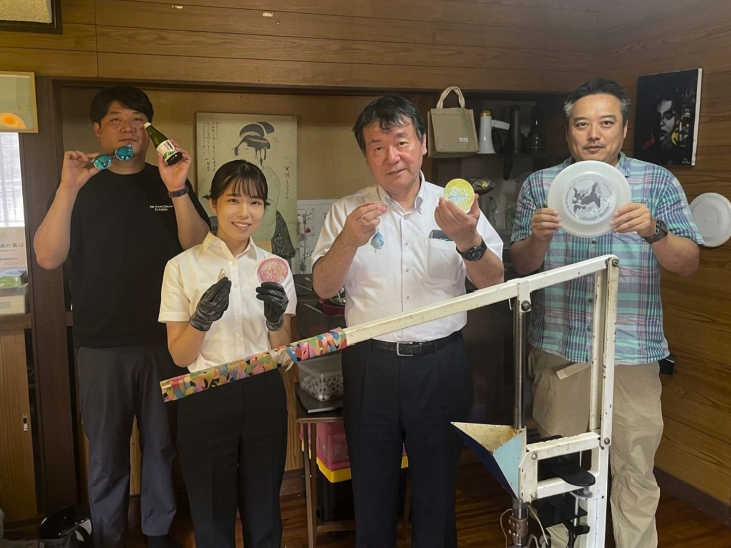 Precious Plastic 唐津の工房で、アップサイクルのコースターやキーホルダーを手に並ぶ4名。左から唐津南高校の岡本先生、奈良教育大学大学院の田中さん、及川幸彦教授、唐津Farm&Foodの小嶋