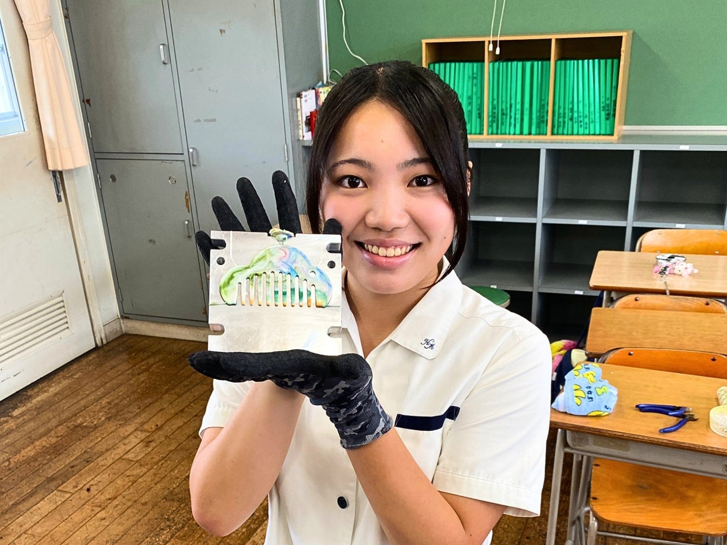 金型から取り出したばかりの櫛を、両手で掲げて見せる生徒