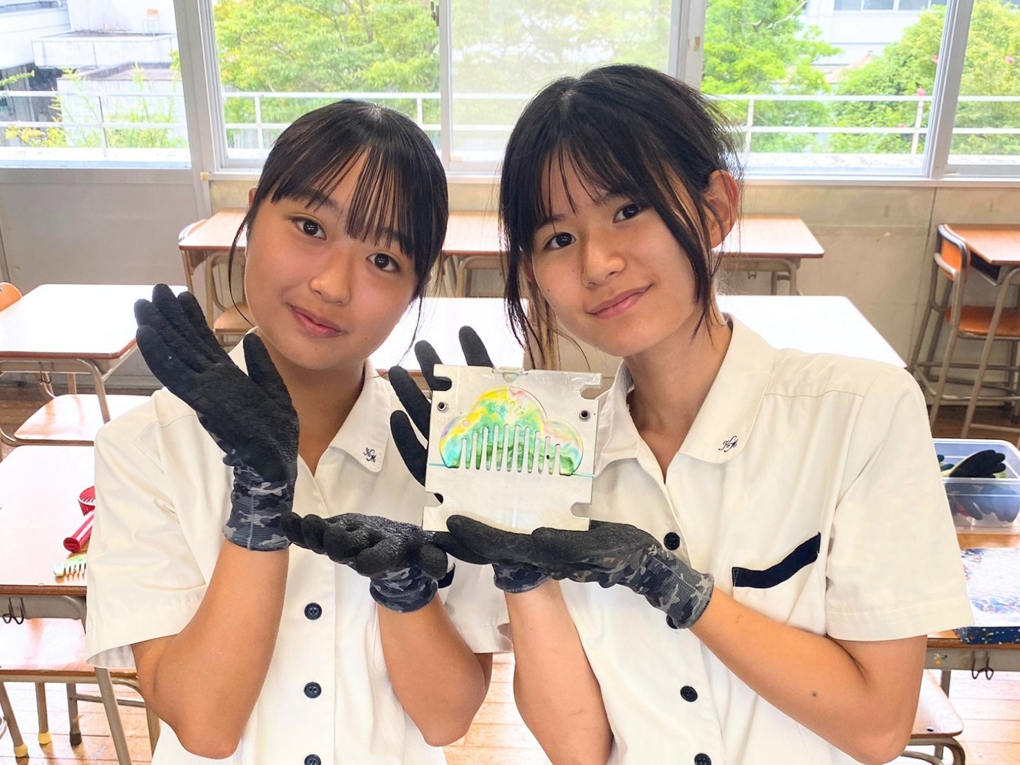 金型に入ったままの櫛を、ふたりで両手に持って見せる生徒