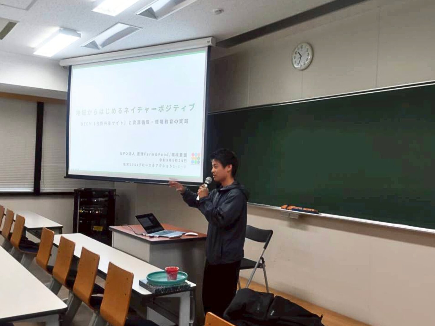佐賀大学の教室で「地域からはじめるネイチャーポジティブ」のタイトルスライドを背にマイクを持って話す登壇者